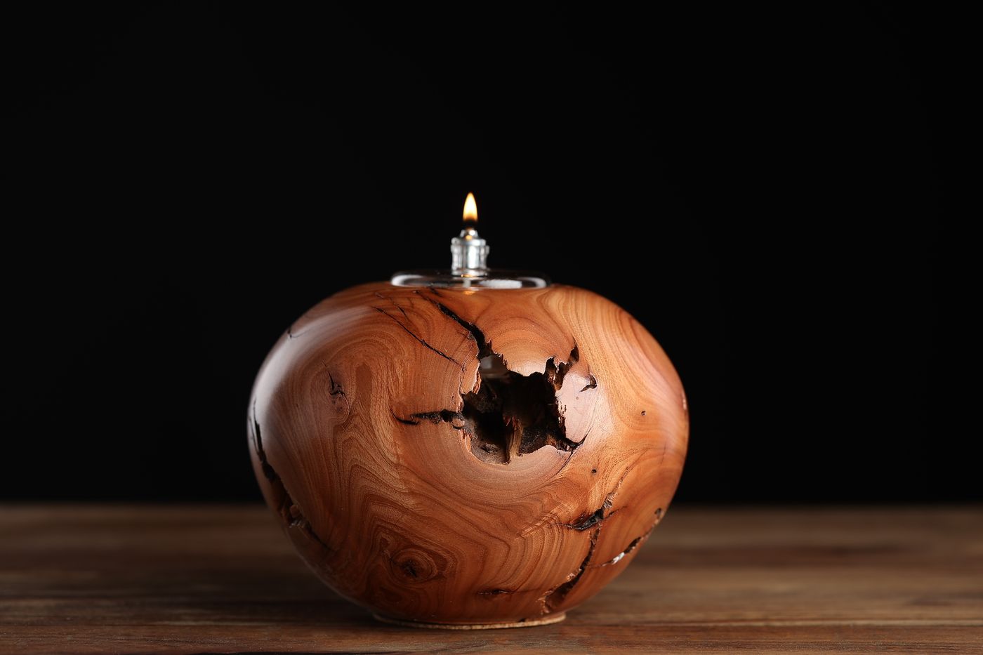 Antelope: a pale honey juniper burl oil lamp with a void opened through one side, lit