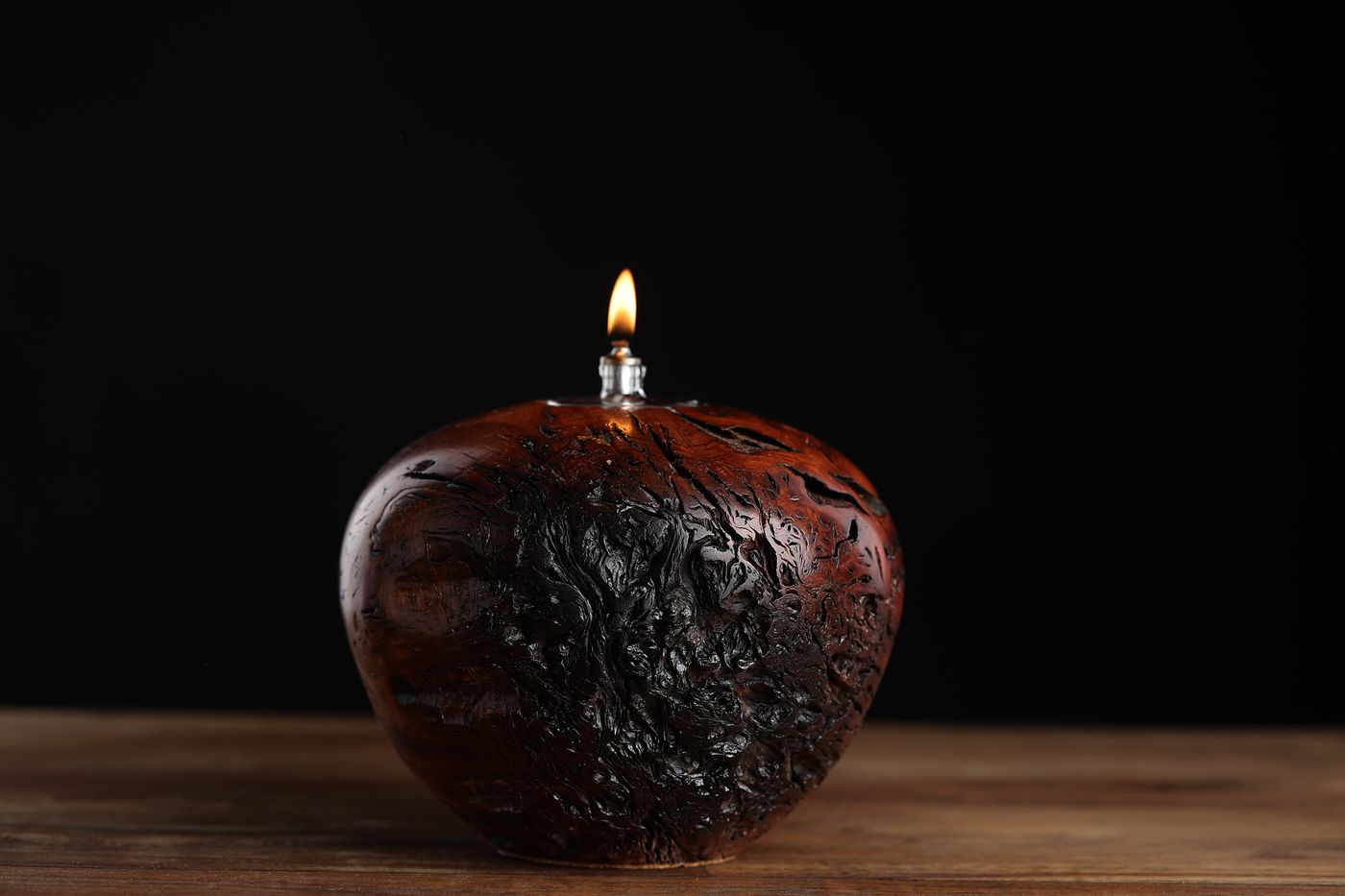 Labyrinth: a deep red-brown juniper burl oil lamp under a crown of char, lit
