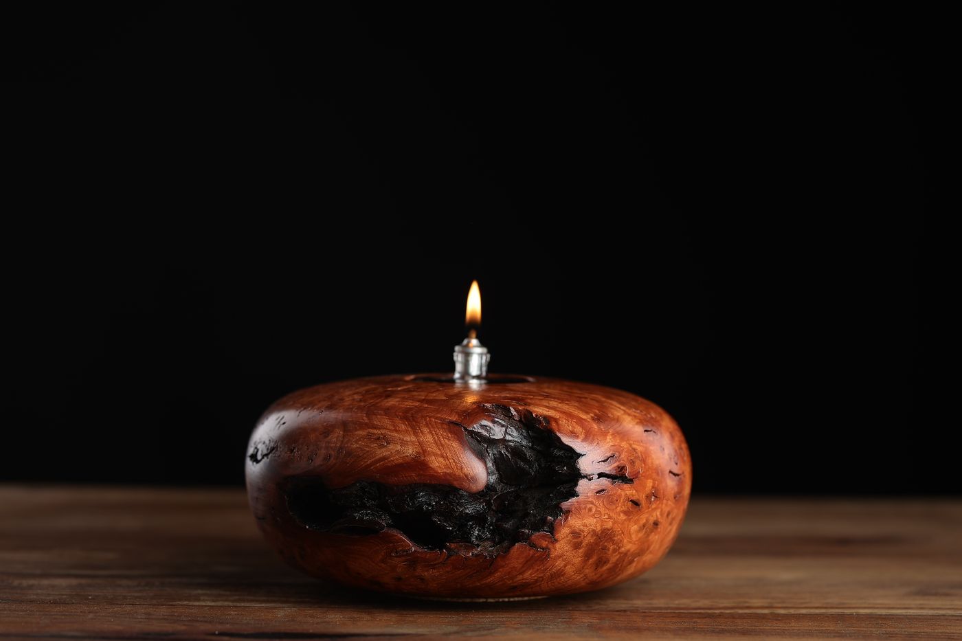 Tsegi: a low oval juniper burl oil lamp in bright orange-red grain, lit