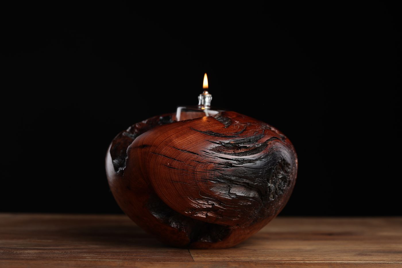 Supai: a full round juniper burl oil lamp with grain that moves like weather, char sweeping one side, lit